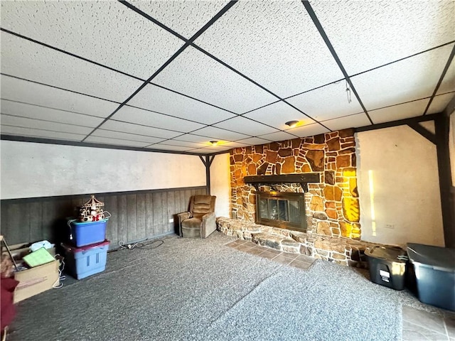 unfurnished living room with carpet flooring, a fireplace, and a drop ceiling