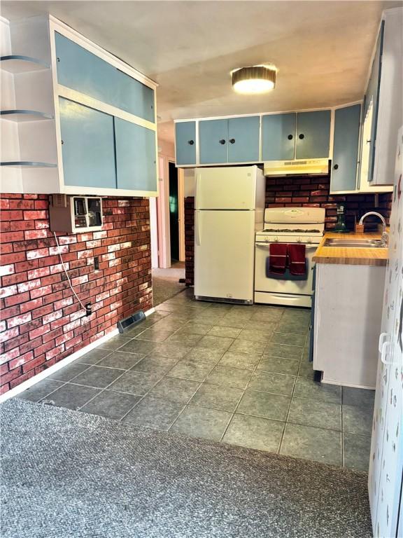 kitchen with wood counters, sink, white appliances, and brick wall