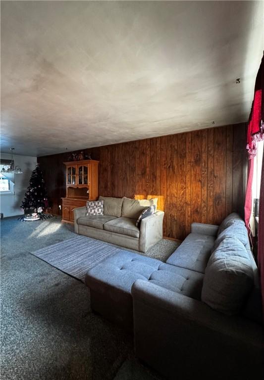 carpeted living room featuring wood walls