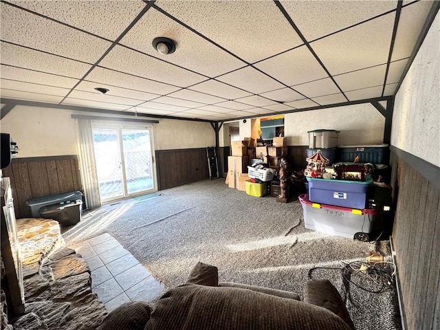 carpeted living room featuring a paneled ceiling and wood walls