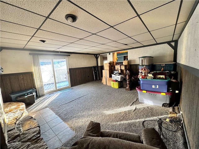 interior space featuring carpet floors, a paneled ceiling, and wood walls