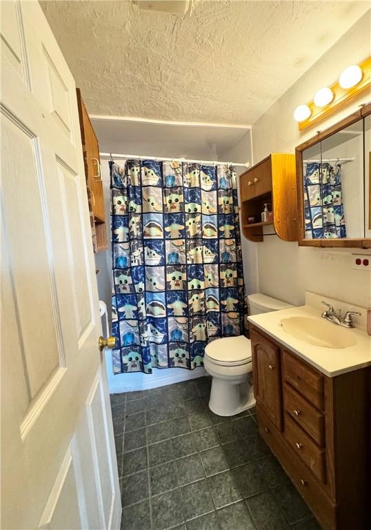 bathroom with vanity, toilet, a shower with shower curtain, and a textured ceiling