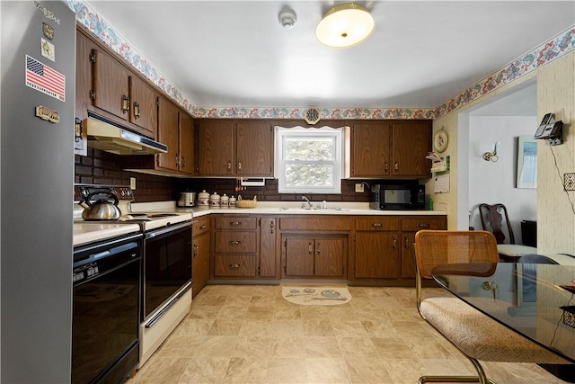 kitchen with light countertops, decorative backsplash, a sink, under cabinet range hood, and black appliances