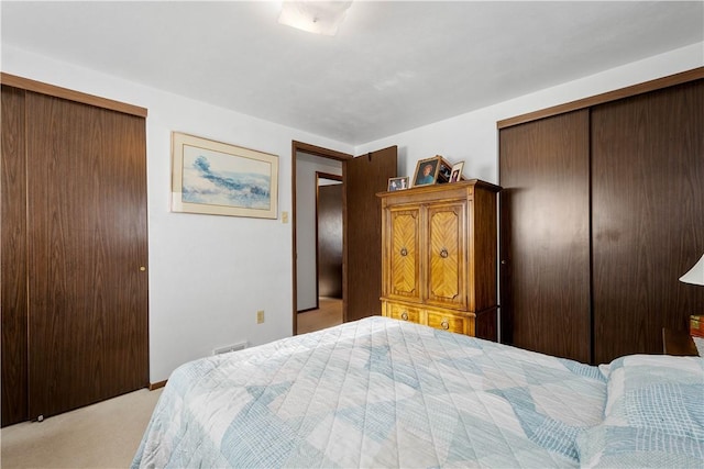 bedroom featuring light carpet and two closets