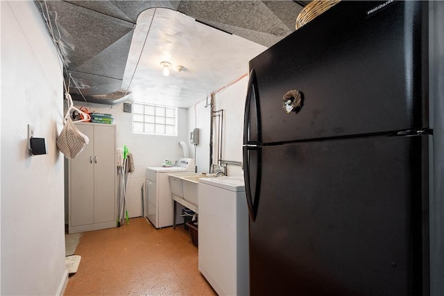 kitchen featuring washer and clothes dryer, freestanding refrigerator, light countertops, light floors, and a sink