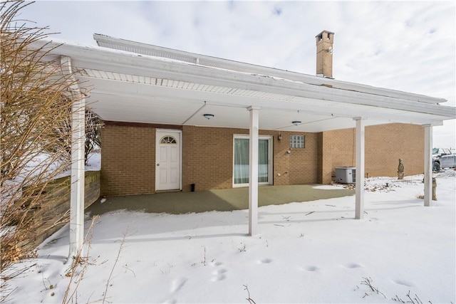 snow covered rear of property with central air condition unit