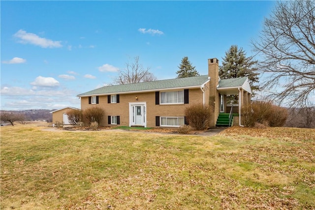 bi-level home with brick siding, a chimney, and a front yard