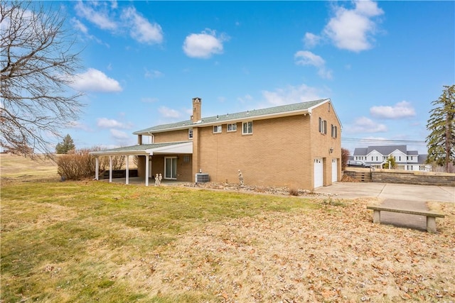 rear view of house featuring central AC unit, a lawn, concrete driveway, a chimney, and an attached garage