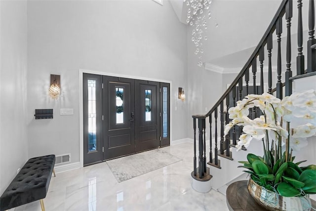 foyer with crown molding and a towering ceiling