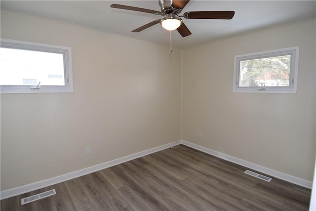 spare room featuring dark wood-type flooring, a wealth of natural light, and ceiling fan