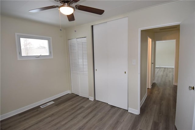 unfurnished bedroom with dark hardwood / wood-style flooring, ornamental molding, and ceiling fan