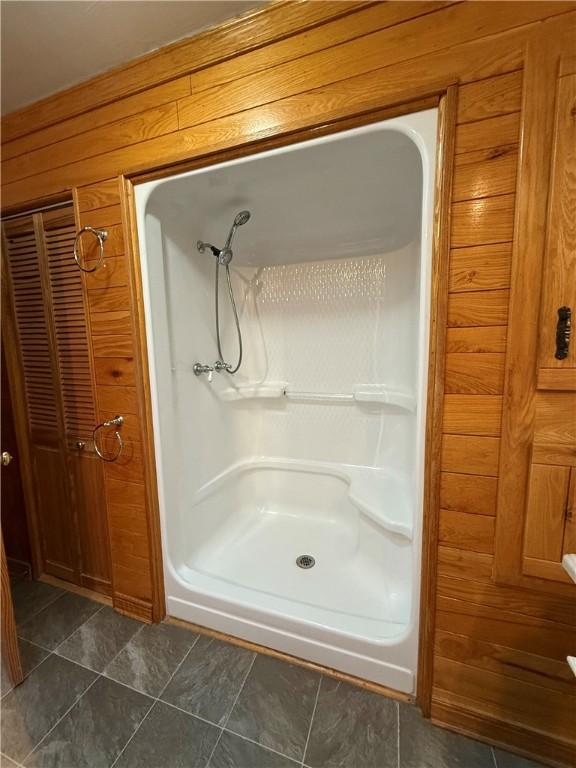 bathroom with wooden walls and a shower