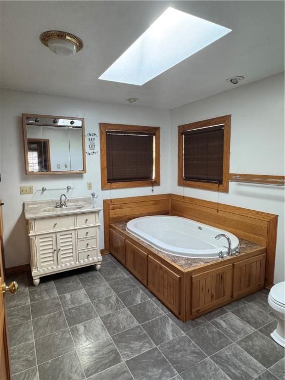 bathroom with a tub to relax in, toilet, a skylight, and vanity