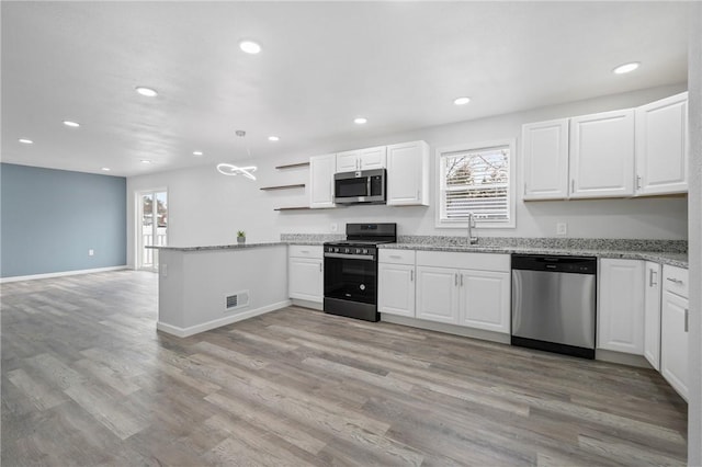 kitchen with a wealth of natural light, sink, white cabinets, kitchen peninsula, and stainless steel appliances