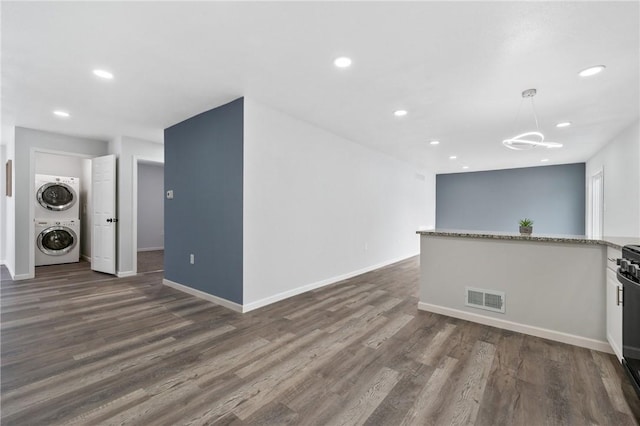 interior space featuring stacked washer and dryer and dark wood-type flooring