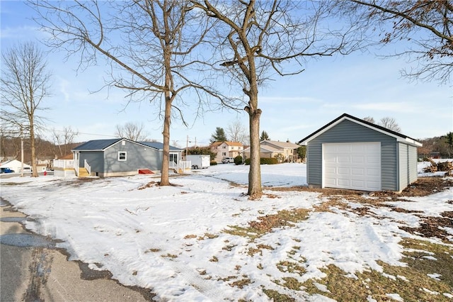 yard covered in snow featuring a garage and an outbuilding