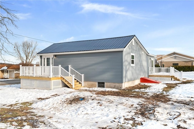 snow covered back of property with a wooden deck