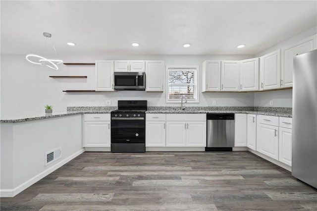 kitchen with appliances with stainless steel finishes, dark hardwood / wood-style floors, pendant lighting, and white cabinets