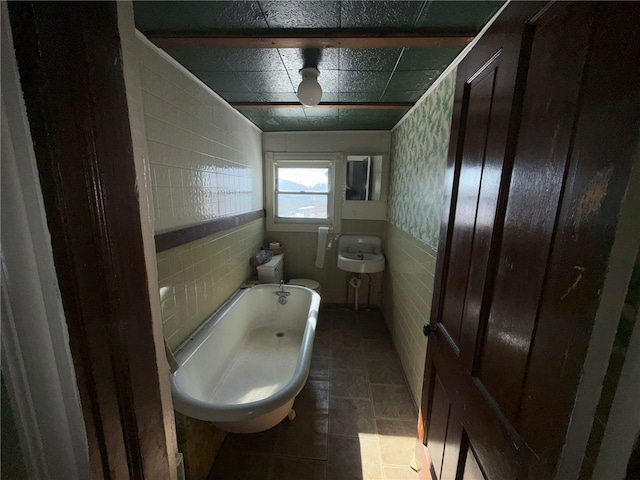 bathroom with tile walls, a bath, and toilet