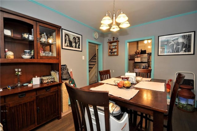 dining space featuring ornamental molding, dark wood-type flooring, and an inviting chandelier