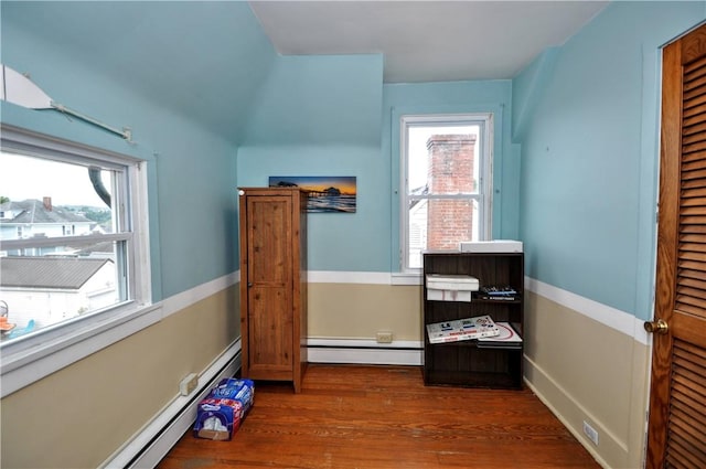 interior space with dark wood-type flooring and a baseboard heating unit