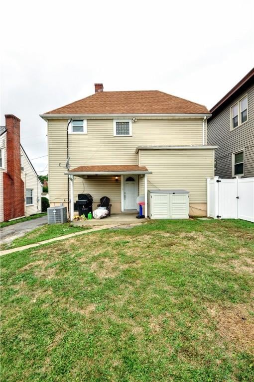 rear view of house with central AC and a yard