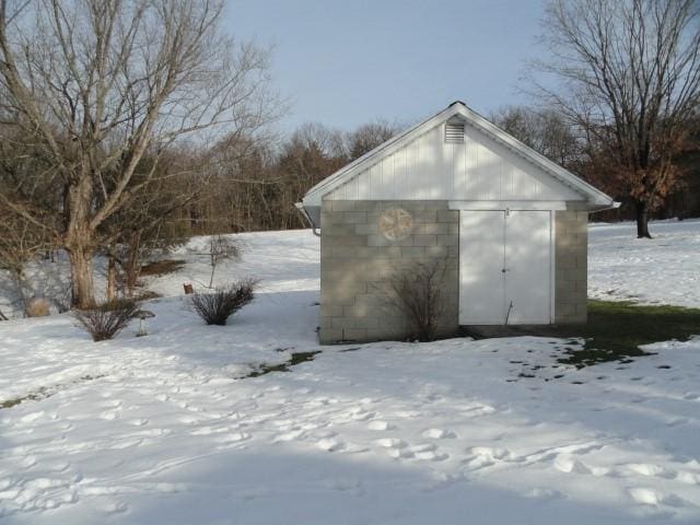 snow covered structure featuring a storage unit and an outdoor structure