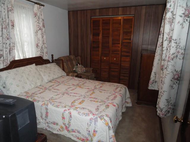 bedroom featuring wood walls, a closet, and carpet flooring