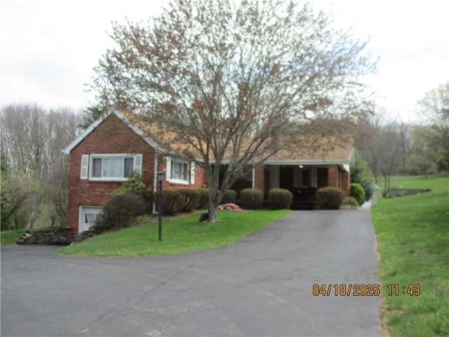 view of front of property with brick siding, aphalt driveway, and a front yard