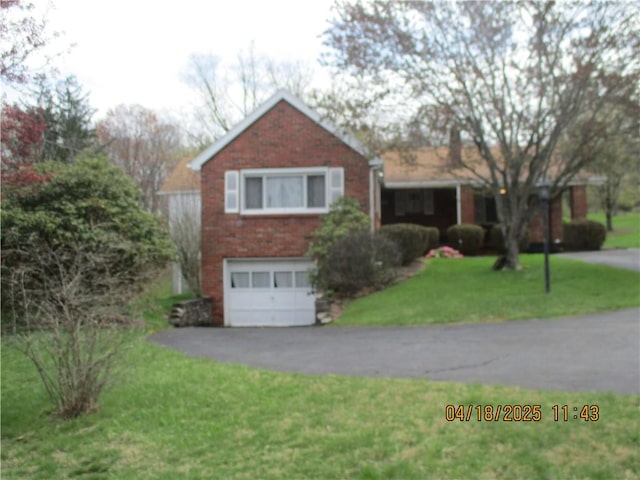 view of front of home featuring a garage, brick siding, a front yard, and aphalt driveway