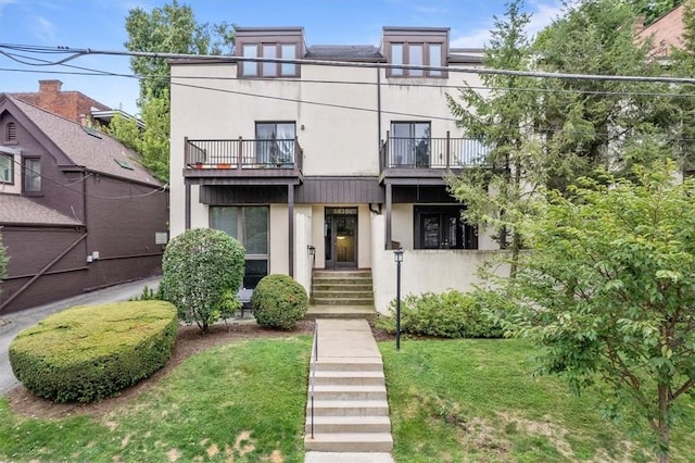 view of front of home featuring a front yard and a balcony