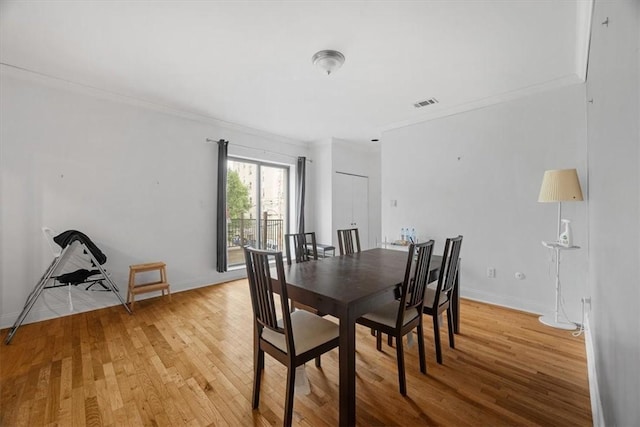 dining room with crown molding and light hardwood / wood-style flooring