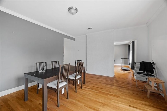 dining area with ornamental molding and light wood-type flooring