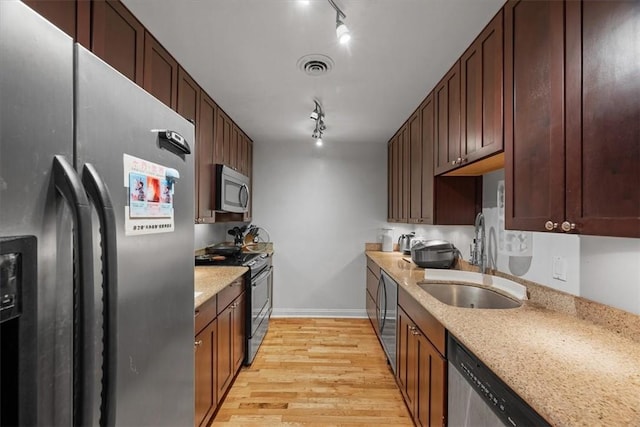 kitchen featuring light stone counters, sink, light hardwood / wood-style flooring, and appliances with stainless steel finishes