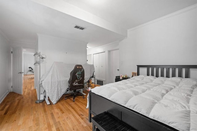 bedroom with crown molding, light hardwood / wood-style flooring, and a closet