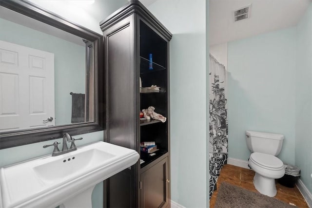 bathroom featuring a shower with curtain, toilet, and sink