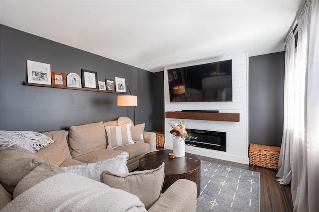 living room featuring dark wood-type flooring and a large fireplace