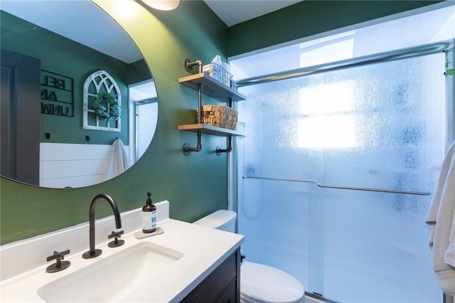 bathroom with vanity, toilet, and a shower with shower door