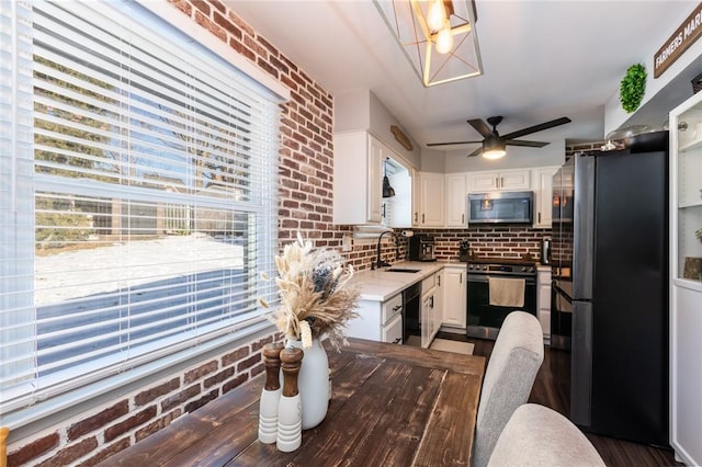 kitchen featuring sink, white cabinets, brick wall, and appliances with stainless steel finishes