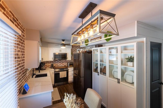 kitchen featuring brick wall, appliances with stainless steel finishes, sink, and white cabinets