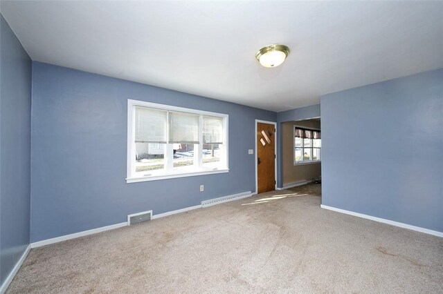 carpeted spare room with a baseboard heating unit