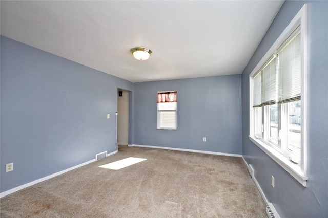 empty room featuring a baseboard heating unit and light carpet