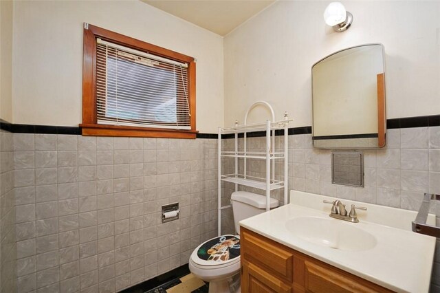 bathroom with vanity, tile walls, and toilet