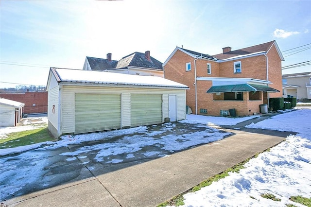 snow covered back of property with an outbuilding and a garage