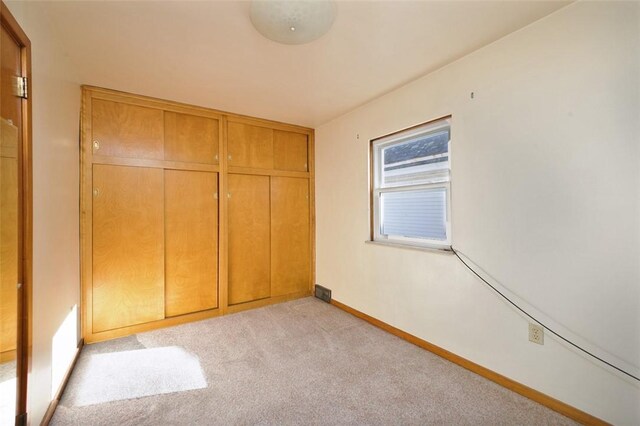 unfurnished bedroom featuring light carpet and a closet