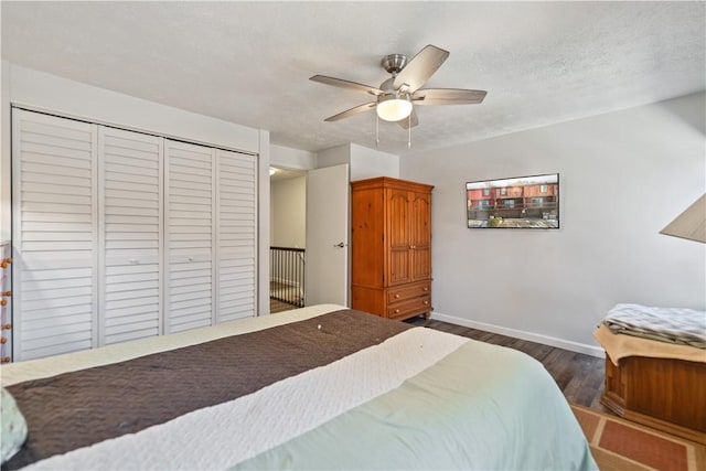 bedroom with dark hardwood / wood-style floors, a textured ceiling, a closet, and ceiling fan