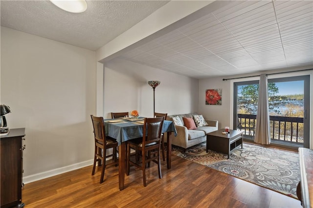 dining space featuring dark wood-type flooring and a textured ceiling