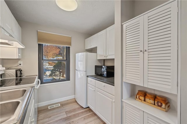 kitchen with sink, white cabinets, white appliances, light hardwood / wood-style floors, and a textured ceiling