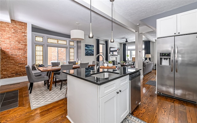 kitchen with white cabinetry, appliances with stainless steel finishes, sink, and a center island with sink