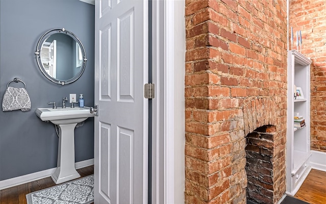 bathroom featuring wood-type flooring and brick wall